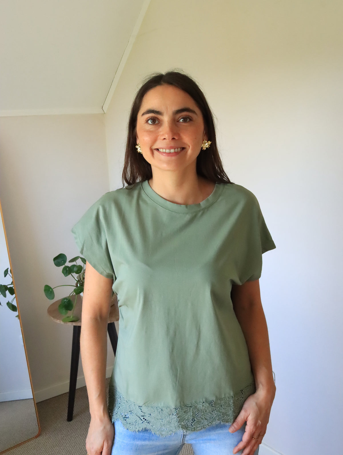 Polera Emma verde con remate de encaje en el ruedo, vista frontal con jeans