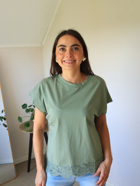 Polera Emma verde con remate de encaje en el ruedo, vista frontal con jeans