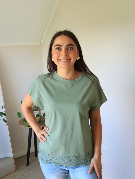 Polera Emma verde con encaje en el ruedo, de frente con la mano en la cintura