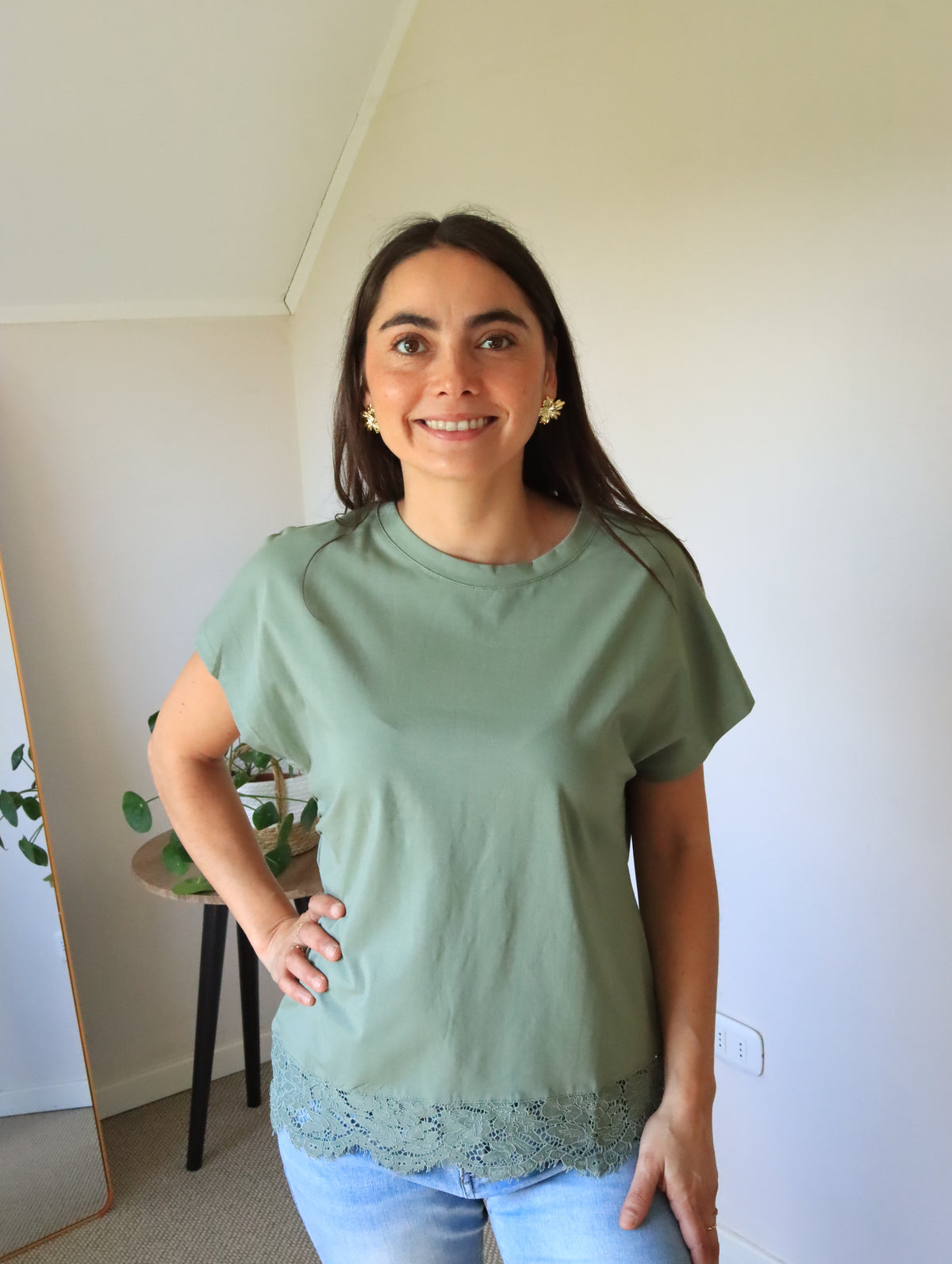 Polera Emma verde con encaje en el ruedo, de frente con la mano en la cintura