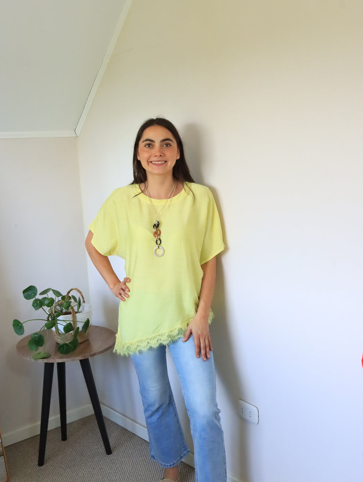 Polera Jana amarilla con la mano en la cintura y jeans celestes
