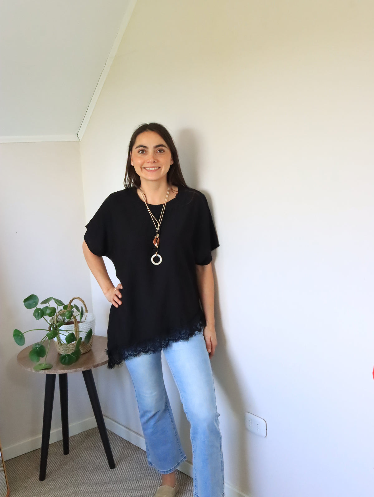Polera Jana negra con encaje en el ruedo, de cuerpo entero con jeans