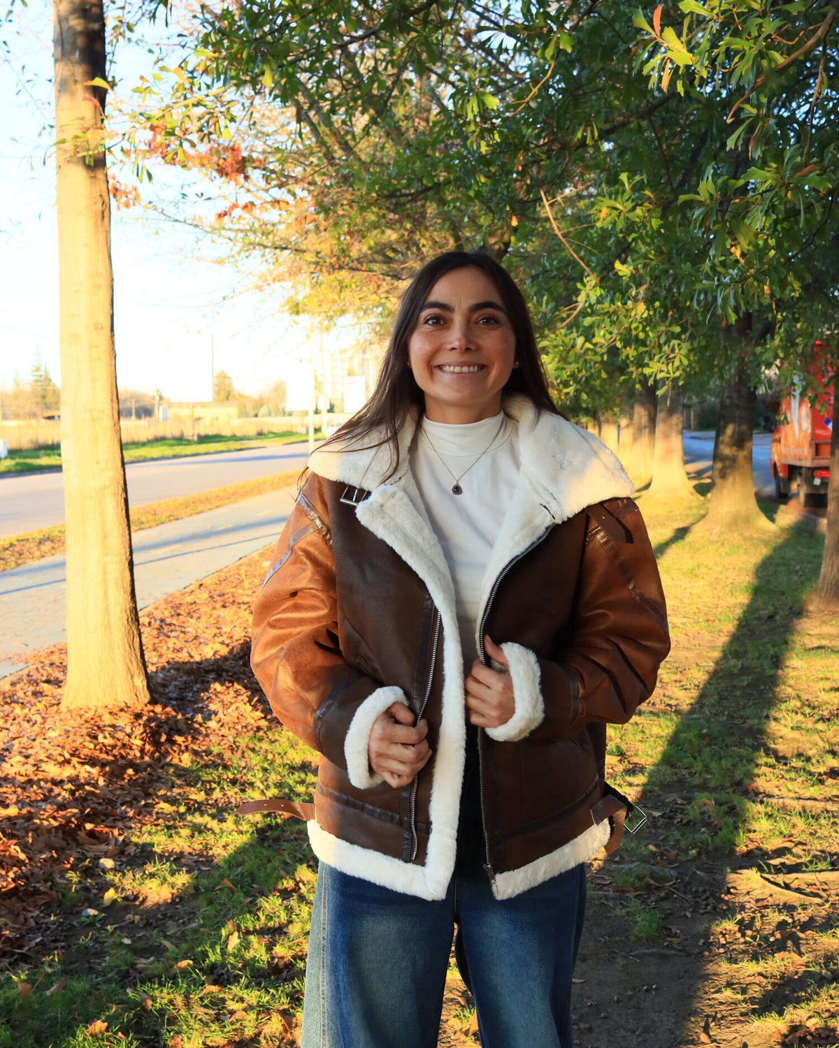 Valeria con chaqueta aviador café con chiporro en una alameda al atardecer