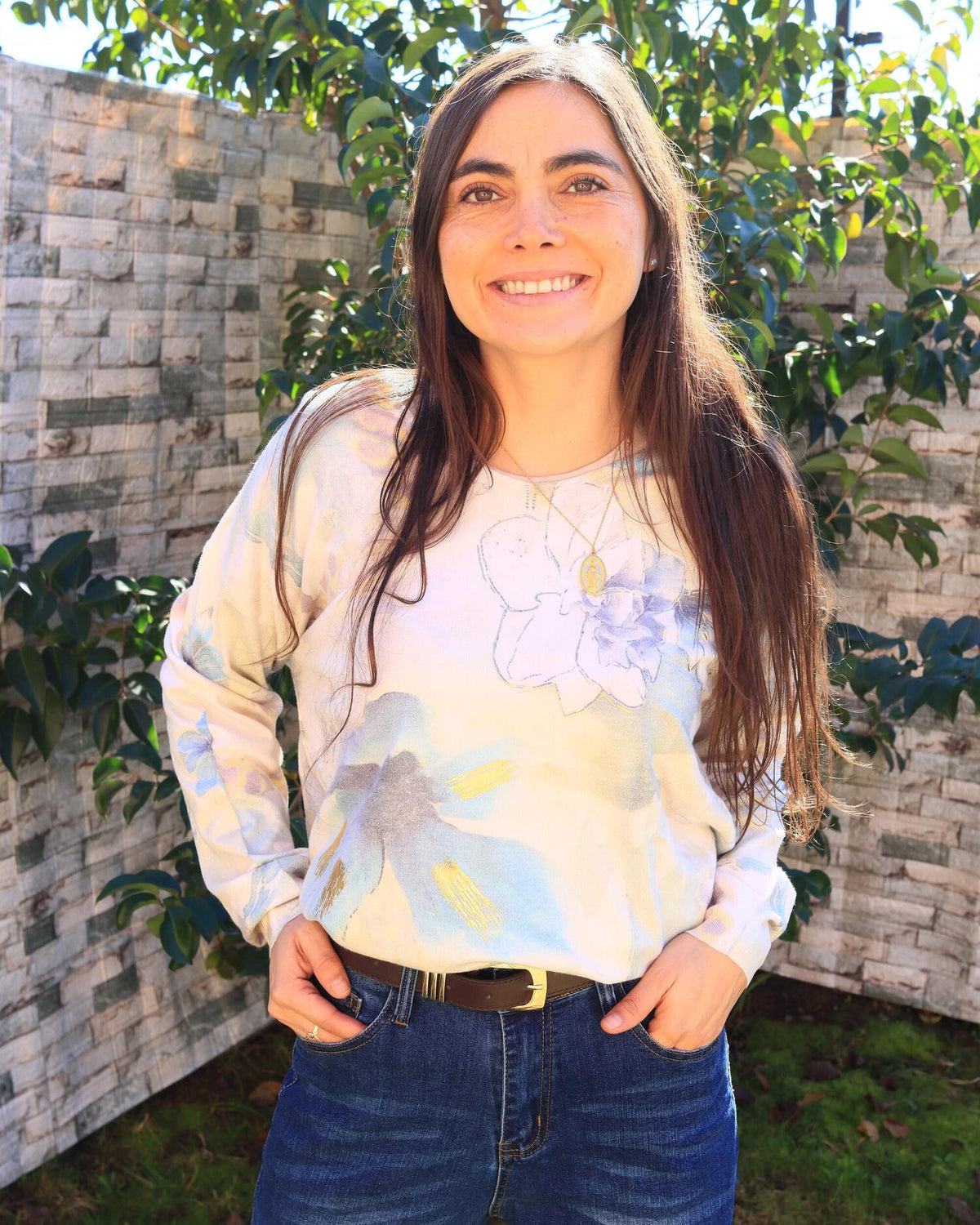 Valeria sonriendo con sweater crudo de flores en acuarela y jeans