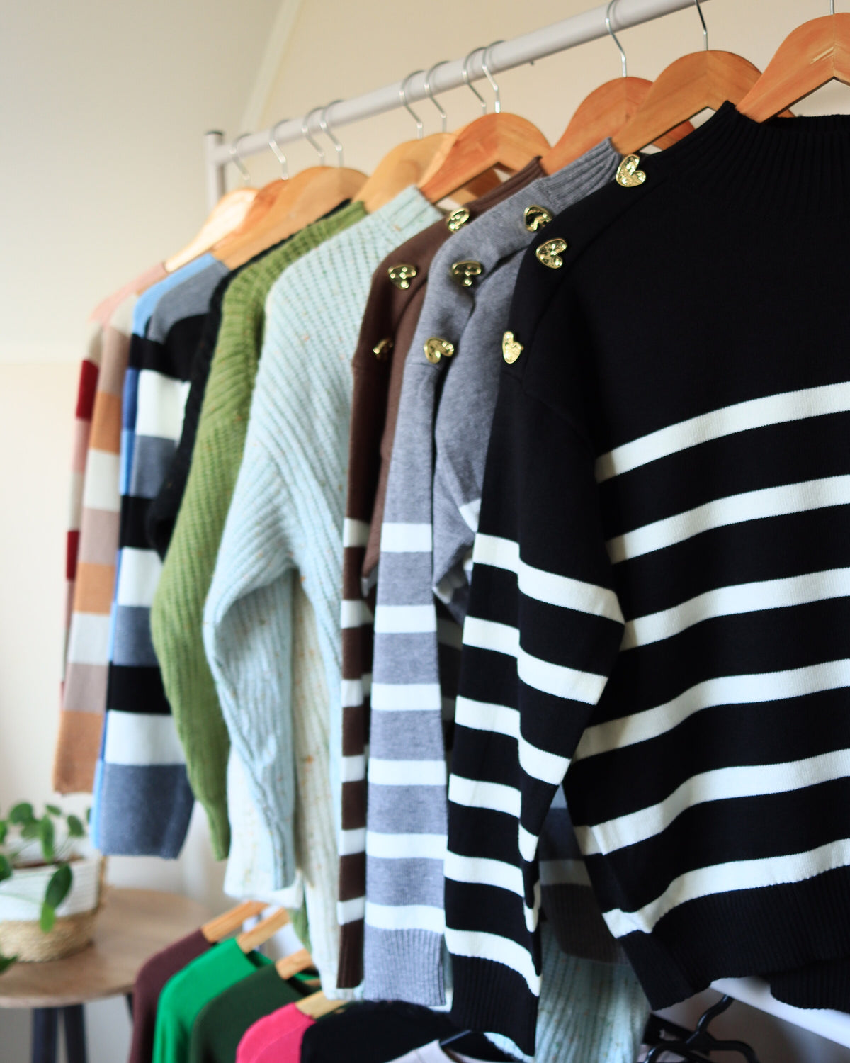 Perchero ASIRI con sweaters a rayas y de colores