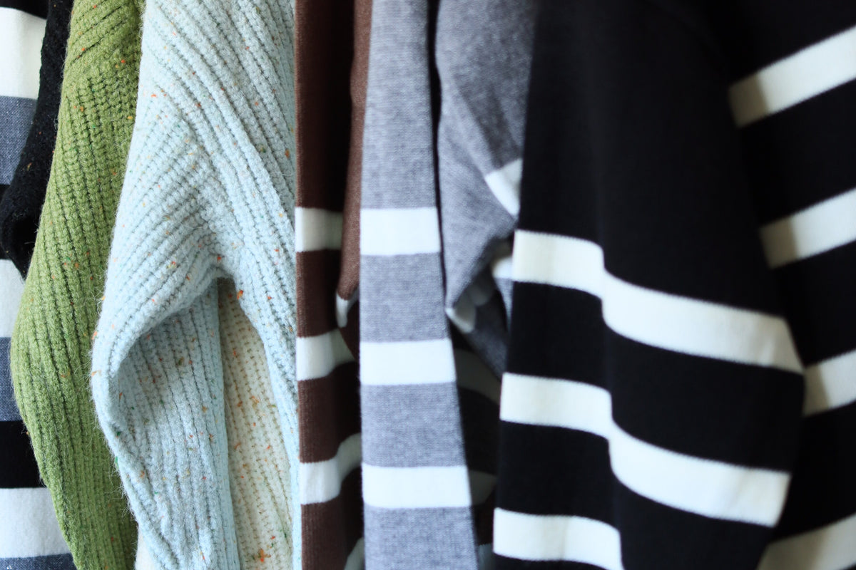 Perchero de sweaters a rayas y de colores con botones de corazón dorado